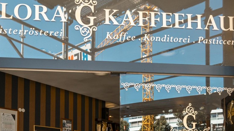 Eingang des Glora Kaffeehauses mit dekorativem Schriftzug auf der Glasfront. Im Hintergrund sind Baukr&auml;ne zu sehen., &copy; SMG, Sarah Schmid
