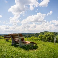 Ruheliege auf einer grünen Wiese am Aussichtspunkt "Hohe Tanne" mit Blick auf eine hügelige Landschaft und einen bewölkten Himmel., © agentur arcos/Niki Eilers