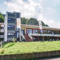 Die Jugendherberge Bad Urach liegt inmitten grüner Natur. Das moderne Gebäude hat große Fenster und ist von Bäumen umgeben. Die Jugendherberge Bad Urach liegt inmitten grüner Natur. Das moderne Gebäude hat große Fenster und ist von Bäumen umgeben.
