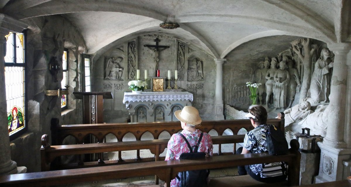 Zwei Personen sitzen auf Kirchenbänken in der Felsenkapelle und schauen auf den Altar., © Touristik- und Marketing GmbH Zwei Personen sitzen auf Kirchenbänken in der Felsenkapelle und schauen auf den Altar., © Touristik- und Marketing GmbH