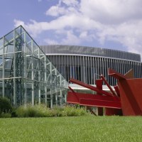 Glasgebäude und rote Skulptur im Stadthallenpark Sindelfingen, umgeben von grüner Wiese und blauem Himmel., © Stadt Sindelfingen