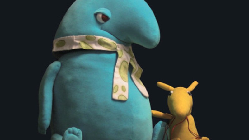 Zwei Stofftiere: ein großes blaues mit Schal und ein kleines gelbes, sitzen nebeneinander vor dunklem Hintergrund., © Theaterwerkstatt Schwäbisch Gmünd e.V. Zwei Stofftiere: ein großes blaues mit Schal und ein kleines gelbes, sitzen nebeneinander vor dunklem Hintergrund., © Theaterwerkstatt Schwäbisch Gmünd e.V.