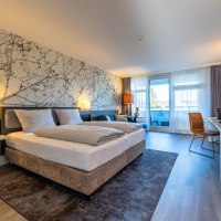 Modernes Hotelzimmer mit Doppelbett, Schreibtisch, Stuhl und Balkon. Helle Farben und stilvolle Wandgestaltung mit Naturmotiv., © MASEVEN Stuttgart SI-Centrum Modernes Hotelzimmer mit Doppelbett, Schreibtisch, Stuhl und Balkon. Helle Farben und stilvolle Wandgestaltung mit Naturmotiv., © MASEVEN Stuttgart SI-Centrum