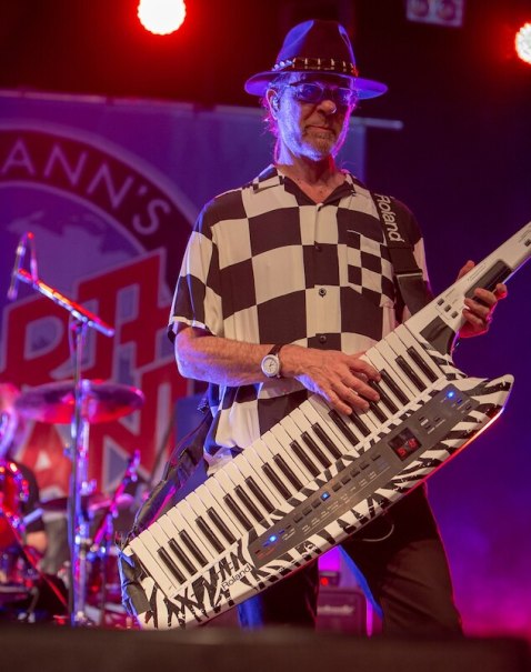 Ein Musiker mit Hut spielt eine Keytar auf der Bühne. Im Hintergrund ist ein Banner von Manfred Mann's Earth Band zu sehen., © die Halle Kulturinitiative e.V.