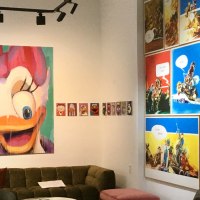 Eine Galerie zeigt bunte Pop-Art-Gemälde von Comicfiguren und moderne Kunstwerke. Ein großes Bild einer Ente dominiert die Wand. Ein Sofa steht im Raum., © GALERIE Z Eine Galerie zeigt bunte Pop-Art-Gemälde von Comicfiguren und moderne Kunstwerke. Ein großes Bild einer Ente dominiert die Wand. Ein Sofa steht im Raum., © GALERIE Z