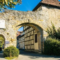 Ein altes Stadttor in Marbach am Neckar, flankiert von Fachwerkhäusern und umgeben von grüner Vegetation unter blauem Himmel., © Stuttgart-Marketing GmbH, Sarah Schmid Ein altes Stadttor in Marbach am Neckar, flankiert von Fachwerkhäusern und umgeben von grüner Vegetation unter blauem Himmel., © Stuttgart-Marketing GmbH, Sarah Schmid