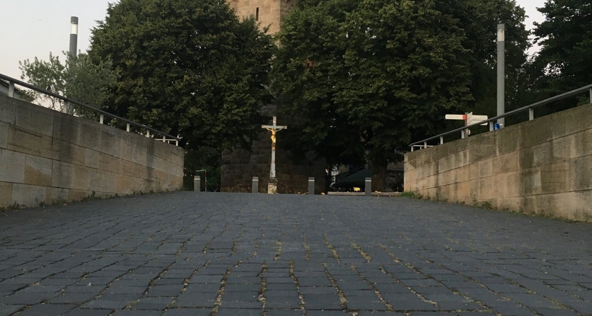 Pflasterweg mit roter Blumenmarkierung, führt zu einem historischen Turm, umgeben von Bäumen., © Touristik und Marketing GmbH Pflasterweg mit roter Blumenmarkierung, führt zu einem historischen Turm, umgeben von Bäumen., © Touristik und Marketing GmbH