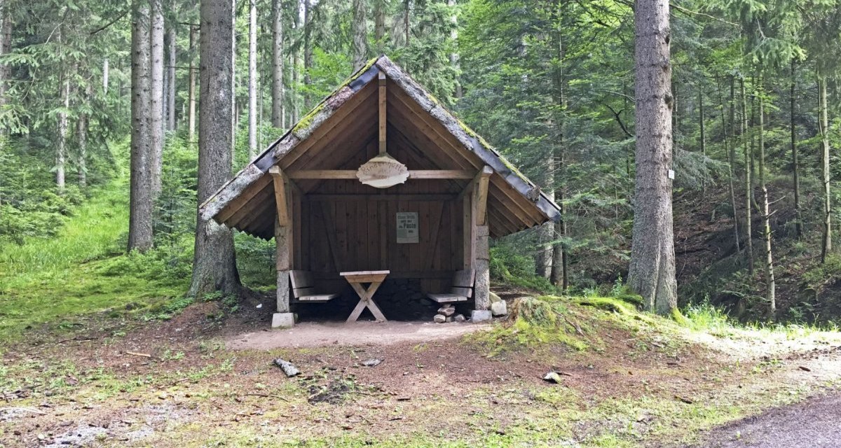 Kleine Holzhütte im Wald, umgeben von hohen Bäumen. Vor der Hütte stehen ein Tisch und Bänke. Der Boden ist mit Moos und Gras bedeckt., © www.pro-cycl.de Kleine Holzhütte im Wald, umgeben von hohen Bäumen. Vor der Hütte stehen ein Tisch und Bänke. Der Boden ist mit Moos und Gras bedeckt., © www.pro-cycl.de