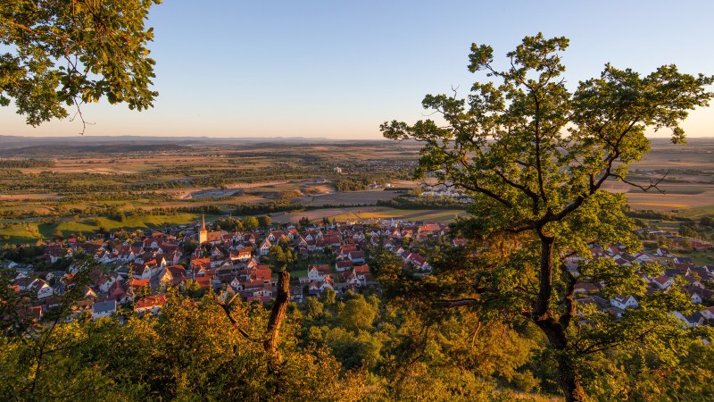 Blick auf ein Dorf im Heckengäu, umgeben von Feldern und Bäumen. Die Abendsonne taucht die Landschaft in warmes Licht., © Stuttgart-Marketing GmbH, Achim Mende