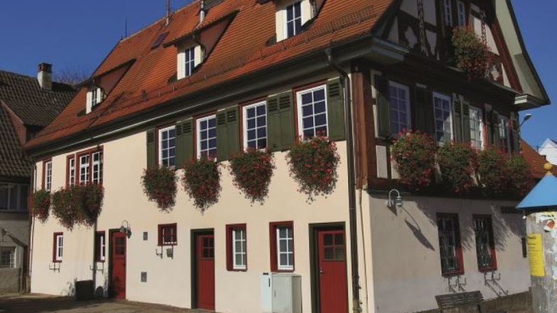 Historisches Rathaus in Ötlingen mit rotem Satteldach, Fachwerkdetails und Blumenkästen an den Fenstern. Sonniger Tag, blauer Himmel., © Stadt Kirchheim unter Teck Historisches Rathaus in Ötlingen mit rotem Satteldach, Fachwerkdetails und Blumenkästen an den Fenstern. Sonniger Tag, blauer Himmel., © Stadt Kirchheim unter Teck