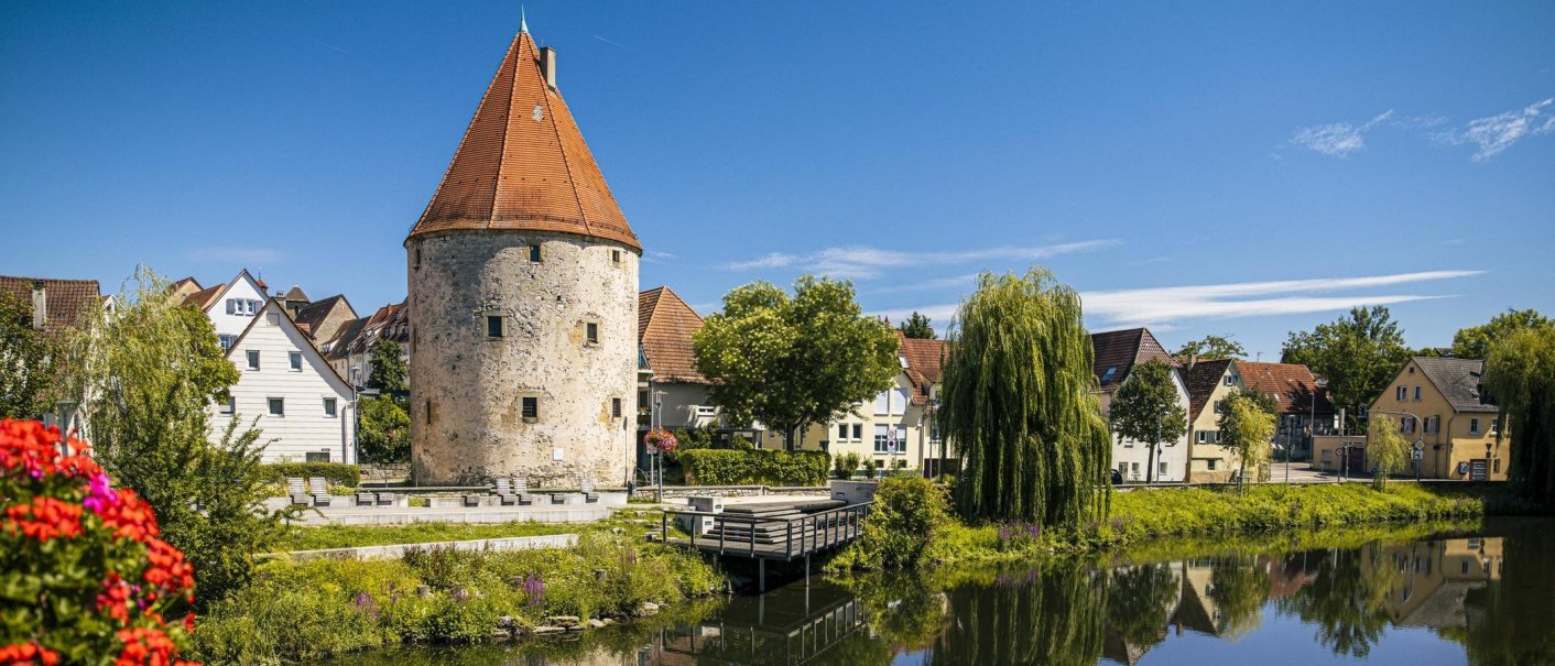 Runder Turm mit rotem Dach am Fluss, umgeben von Häusern und Bäumen, blauer Himmel., © Stuttgart-Marketing GmbH, Sarah Schmid