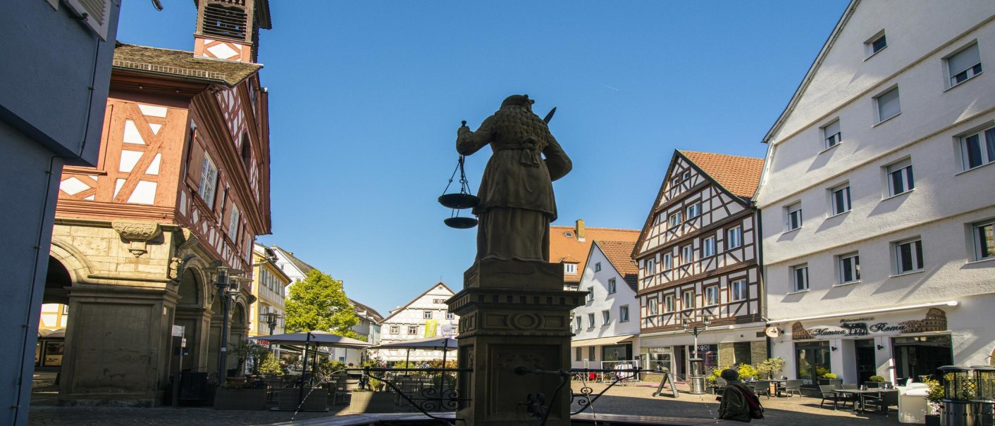 Der Marktplatz in Waiblingen zeigt Fachwerkhäuser und eine Statue im Vordergrund. Der Himmel ist klar und blau., © SMG, Sarah Schmid Der Marktplatz in Waiblingen zeigt Fachwerkhäuser und eine Statue im Vordergrund. Der Himmel ist klar und blau., © SMG, Sarah Schmid
