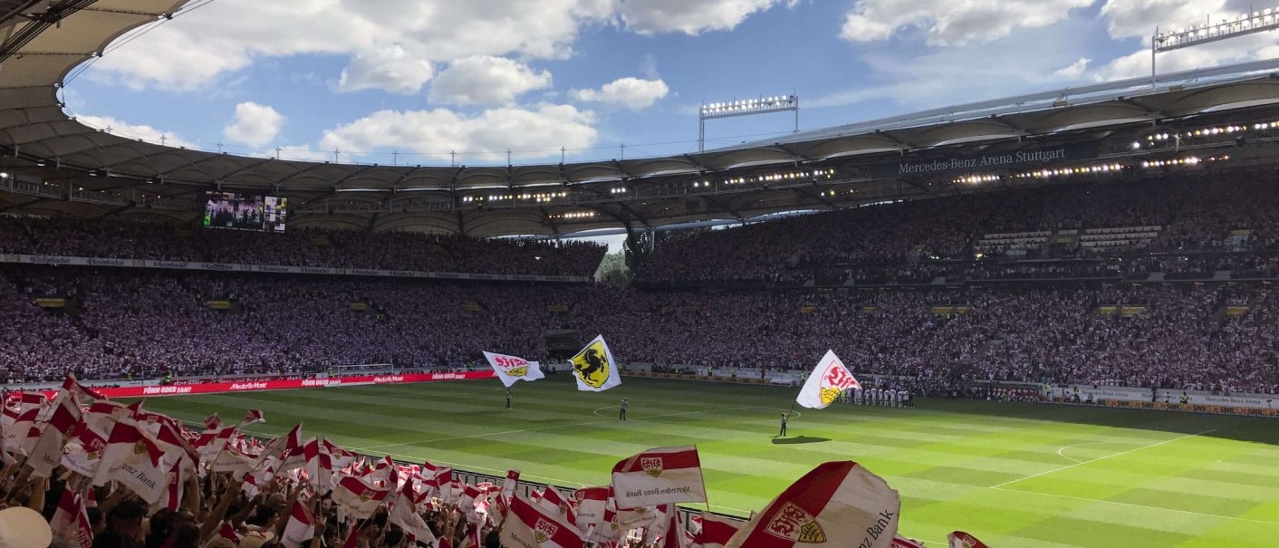 Die Mercedes-Benz Arena in Stuttgart ist voll besetzt. Fans schwenken Fahnen, w&auml;hrend das Spielfeld im Sonnenlicht liegt., &copy; Stuttgart-Marketing GmbH