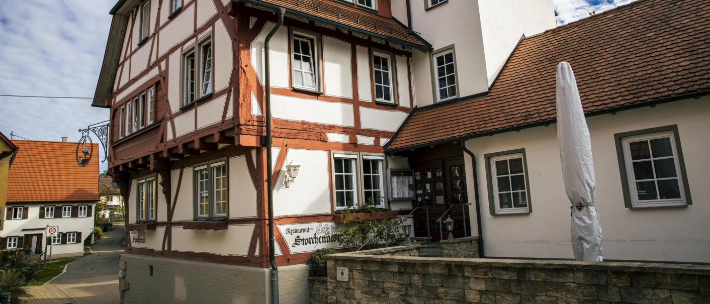 Fachwerkhaus mit Schild "Ristorante Pizzeria Storchennest". Ein geschlossener Sonnenschirm steht davor. Im Hintergrund sind weitere Gebäude zu sehen., © Stuttgart Marketing GmbH, Sarah Schmid Fachwerkhaus mit Schild "Ristorante Pizzeria Storchennest". Ein geschlossener Sonnenschirm steht davor. Im Hintergrund sind weitere Gebäude zu sehen., © Stuttgart Marketing GmbH, Sarah Schmid
