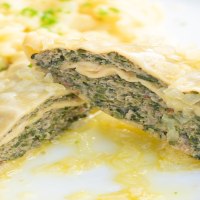 Nahaufnahme von Maultaschen mit einer Füllung aus Fleisch und Kräutern, serviert mit Kartoffelsalat auf einem weißen Teller., © Herr Kächele - Schwäbisches für Schleckige GmbH Nahaufnahme von Maultaschen mit einer Füllung aus Fleisch und Kräutern, serviert mit Kartoffelsalat auf einem weißen Teller., © Herr Kächele - Schwäbisches für Schleckige GmbH