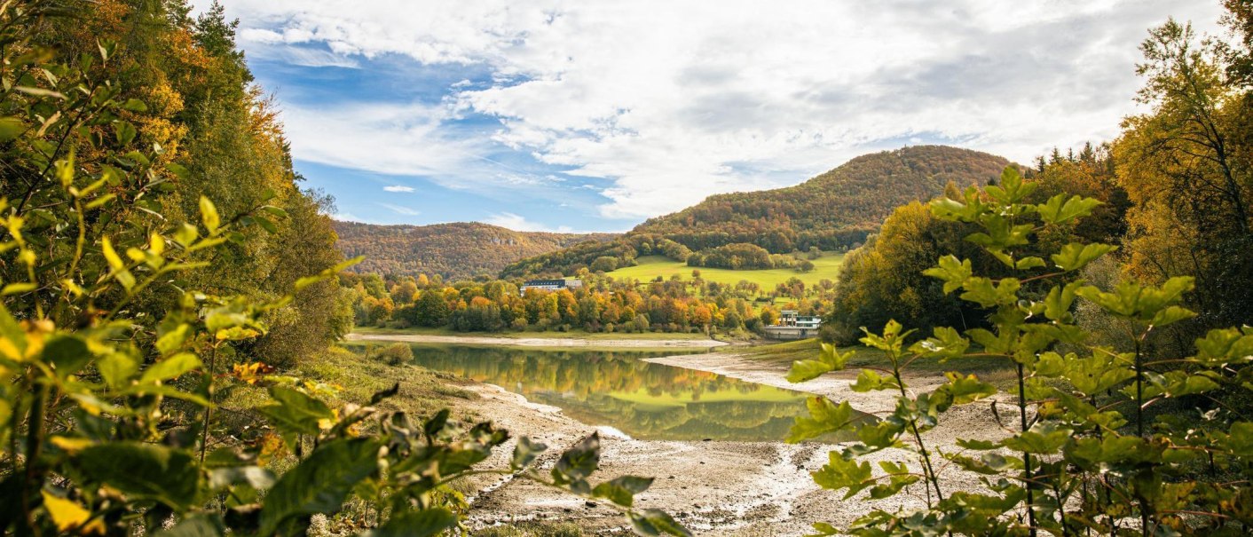 Herbstliche Landschaft am Glems Stausee in Metzingen. Bunte B&auml;ume und H&uuml;gel spiegeln sich im ruhigen Wasser wider., &copy; SMG, Sarah Schmid