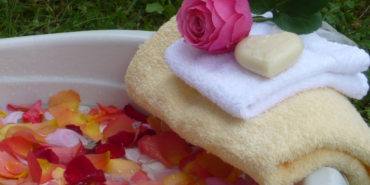 Rosenblätter in einer Schale, darauf Handtücher, eine Rose und herzförmige Seife für ein Wellness-Erlebnis., © Hotel Hochwald