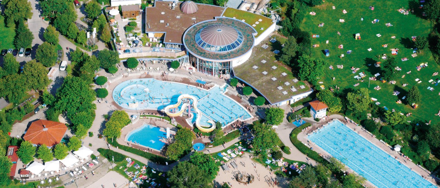 Luftaufnahme eines Freibads mit mehreren Schwimmbecken, Rutschen und einer großen Liegewiese. Menschen entspannen und schwimmen., © Wunndebad Winnenden Luftaufnahme eines Freibads mit mehreren Schwimmbecken, Rutschen und einer großen Liegewiese. Menschen entspannen und schwimmen., © Wunndebad Winnenden
