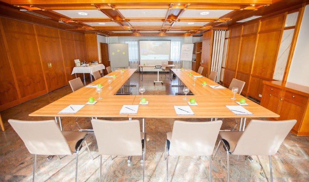 Heller Konferenzraum mit U-förmigem Tisch, Stühlen, Notizblöcken und Gläsern. Im Hintergrund eine Leinwand und Präsentationsausrüstung., © Hotel Waldhorn Heller Konferenzraum mit U-förmigem Tisch, Stühlen, Notizblöcken und Gläsern. Im Hintergrund eine Leinwand und Präsentationsausrüstung., © Hotel Waldhorn