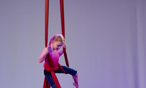 Ein M&auml;dchen &uuml;bt Luftakrobatik an roten T&uuml;chern in einem Workshop. Sie tr&auml;gt ein pinkes Oberteil und blaue Leggings., &copy; Kunstschule Labyrinth