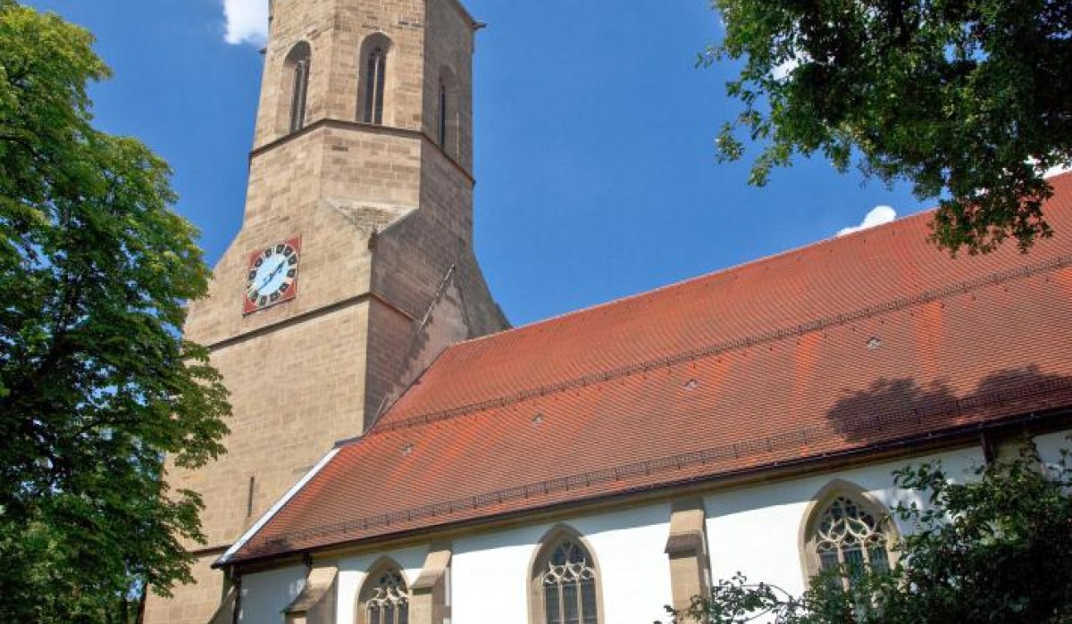 Kirche mit hohem Turm und roten Dachziegeln, umgeben von Bäumen. Der Himmel ist blau mit wenigen Wolken., © Waiblingen - Stuttgart-Marketing GmbH Kirche mit hohem Turm und roten Dachziegeln, umgeben von Bäumen. Der Himmel ist blau mit wenigen Wolken., © Waiblingen - Stuttgart-Marketing GmbH