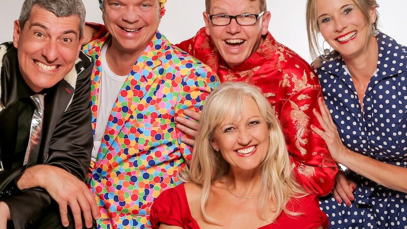 F&uuml;nf Personen in bunten, fr&ouml;hlichen Outfits l&auml;cheln in die Kamera. Sie tragen farbenfrohe Kleidung und scheinen gut gelaunt zu sein., &copy; Mauerwerk GmbH