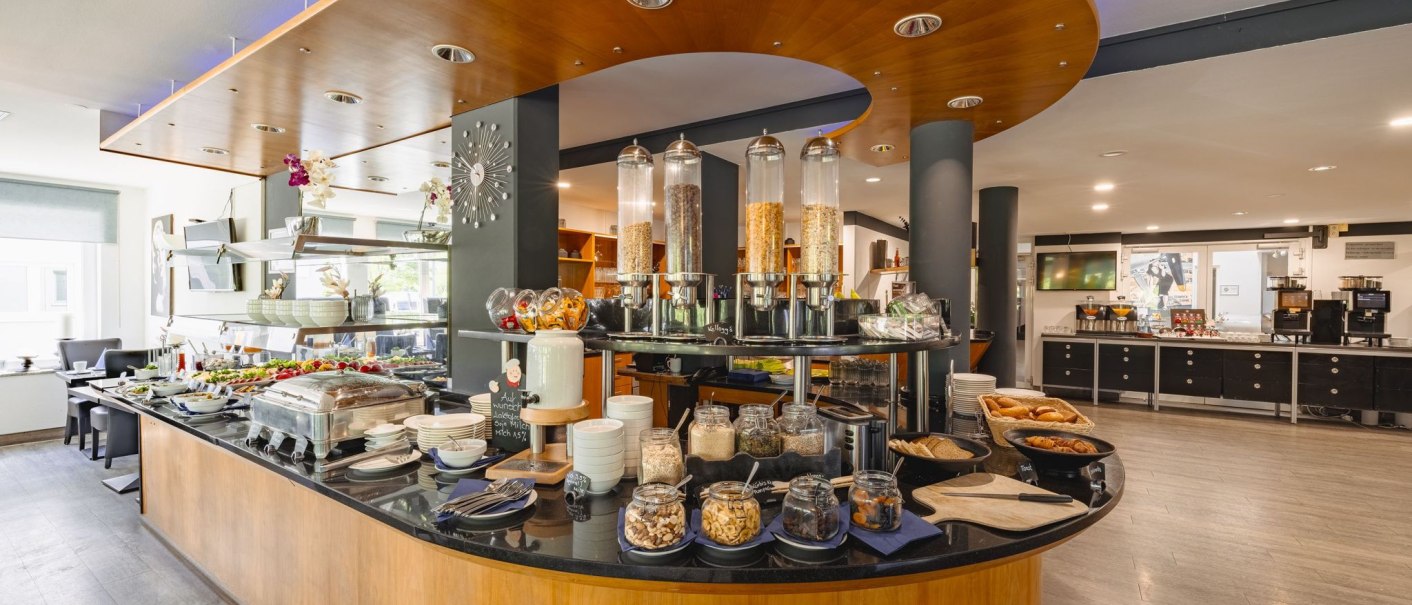 Ein reichhaltiges Frühstücksbuffet mit Müsli, Gebäck und frischen Zutaten in einem modernen Restaurant., © Plaza INN Stuttgart-Filderstadt Ein reichhaltiges Frühstücksbuffet mit Müsli, Gebäck und frischen Zutaten in einem modernen Restaurant., © Plaza INN Stuttgart-Filderstadt
