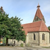 Kirche mit einem  roten Ziegeldach und kleinem Kirchturm, umgeben von gr&uuml;nen B&auml;umen und einem blauen Himmel im Hintergrund., &copy; Petra Natzkowski