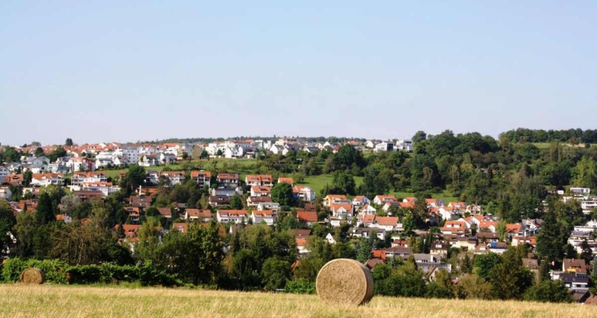 Ein Heuballen auf einem Feld mit Blick auf ein Wohngebiet mit roten Dächern und grünen Bäumen im Hintergrund., © Natur.Nah. Schönbuch & Heckengäu Ein Heuballen auf einem Feld mit Blick auf ein Wohngebiet mit roten Dächern und grünen Bäumen im Hintergrund., © Natur.Nah. Schönbuch & Heckengäu