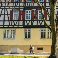 Fachwerkhaus in Kirchheim unter Teck mit einer Statue im Vordergrund. Eine Person geht auf dem Gehweg entlang. Bäume und blauer Himmel im Hintergrund., © Stuttgart-Marketing GmbH, Sarah Schmid Fachwerkhaus in Kirchheim unter Teck mit einer Statue im Vordergrund. Eine Person geht auf dem Gehweg entlang. Bäume und blauer Himmel im Hintergrund., © Stuttgart-Marketing GmbH, Sarah Schmid