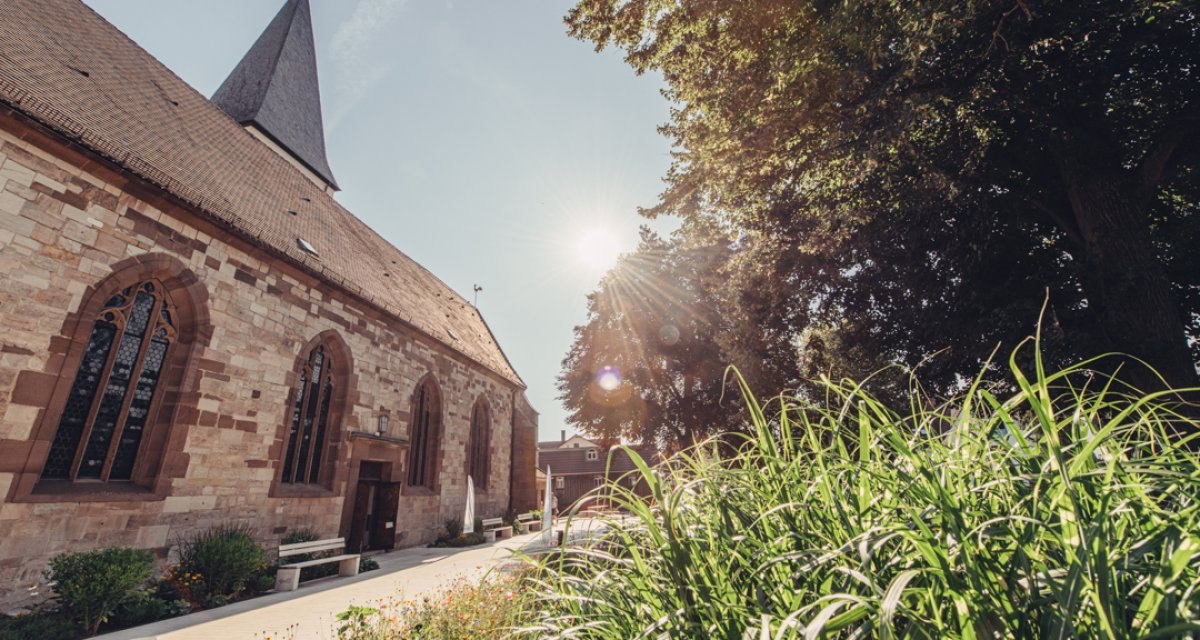 Die Evangelische Stadtkirche Lorch im Sonnenschein, umgeben von grünen Pflanzen und Bäumen. Der Himmel ist klar und die Sonne strahlt hell., © Tourismus Ostalb Die Evangelische Stadtkirche Lorch im Sonnenschein, umgeben von grünen Pflanzen und Bäumen. Der Himmel ist klar und die Sonne strahlt hell., © Tourismus Ostalb