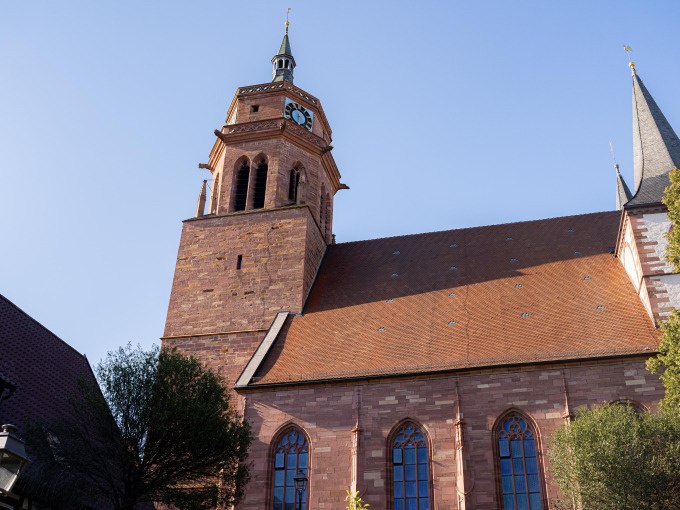 Ein Kirchturm mit Uhr und rotem Ziegeldach ragt in den blauen Himmel. Die gotischen Fenster der Kirche sind gut sichtbar., © Stadtverwaltung Weil der Stadt Ein Kirchturm mit Uhr und rotem Ziegeldach ragt in den blauen Himmel. Die gotischen Fenster der Kirche sind gut sichtbar., © Stadtverwaltung Weil der Stadt