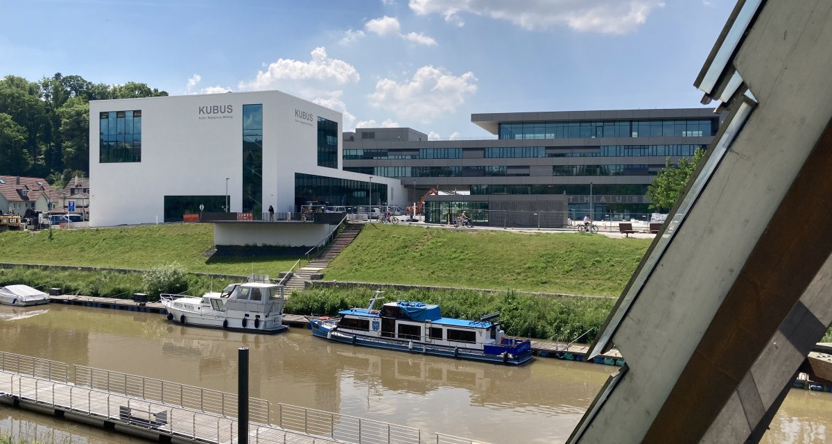 Moderne Gebäude am Flussufer in Remseck am Neckar, mit Booten im Wasser und einem klaren Himmel im Hintergrund., © Remstal Tourismus e. V.