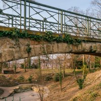 Steinbrücke mit Efeu bewachsen, darunter ein Weg in einem herbstlichen Park mit kahlen Bäumen und vereinzelten Sträuchern., © Thomas Niedermüller Steinbrücke mit Efeu bewachsen, darunter ein Weg in einem herbstlichen Park mit kahlen Bäumen und vereinzelten Sträuchern., © Thomas Niedermüller