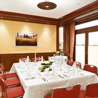 Elegantes Bankettzimmer mit gedecktem Tisch, roten Stühlen und großen Fenstern. An der Wand hängt ein Landschaftsbild., © Hirsch Hotel Elegantes Bankettzimmer mit gedecktem Tisch, roten Stühlen und großen Fenstern. An der Wand hängt ein Landschaftsbild., © Hirsch Hotel