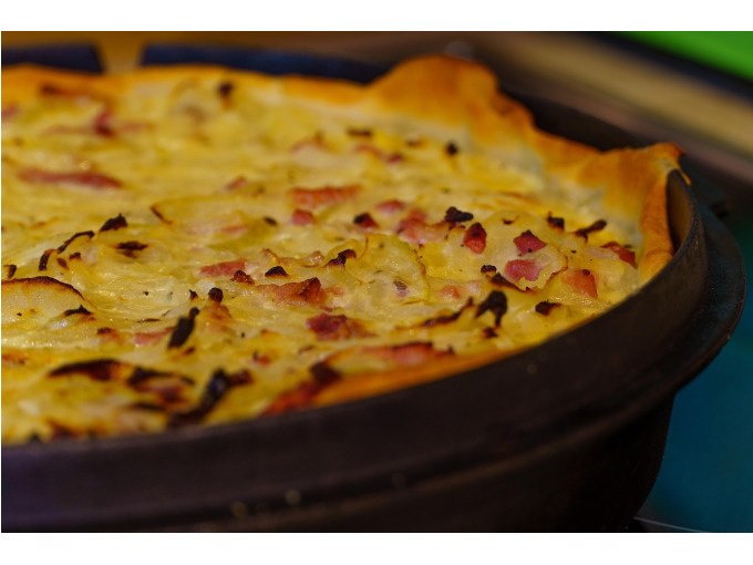 Ein frisch gebackener Zwiebelkuchen in einer runden Backform, goldbraun und mit Speckstückchen belegt., © WTM GmbH Waiblingen
