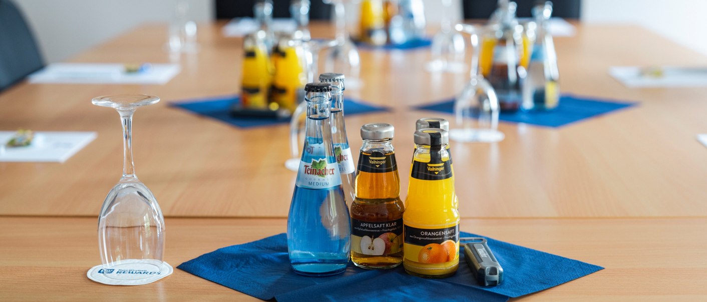 Ein Konferenztisch mit Getränken und umgedrehten Gläsern. Wasser- und Saftflaschen stehen auf blauen Servietten., © Plaza INN Stuttgart-Filderstadt Ein Konferenztisch mit Getränken und umgedrehten Gläsern. Wasser- und Saftflaschen stehen auf blauen Servietten., © Plaza INN Stuttgart-Filderstadt