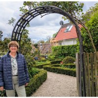 Frau vor einem Gartenbogen, umgeben von gepflegtem Garten mit Hecken und Blumen. Im Hintergrund ein Haus mit rotem Dach., &copy; WTM GmbH Waiblingen