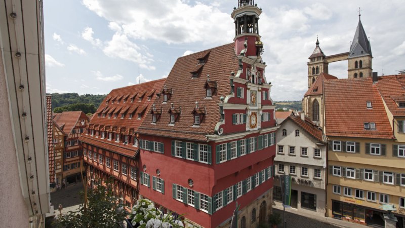 Das Alte Rathaus in Esslingen mit rotem Fachwerk und Turm, umgeben von historischen Gebäuden und blühenden Blumen im Vordergrund., © Esslinger Stadtmarketing & Tourismus GmbH