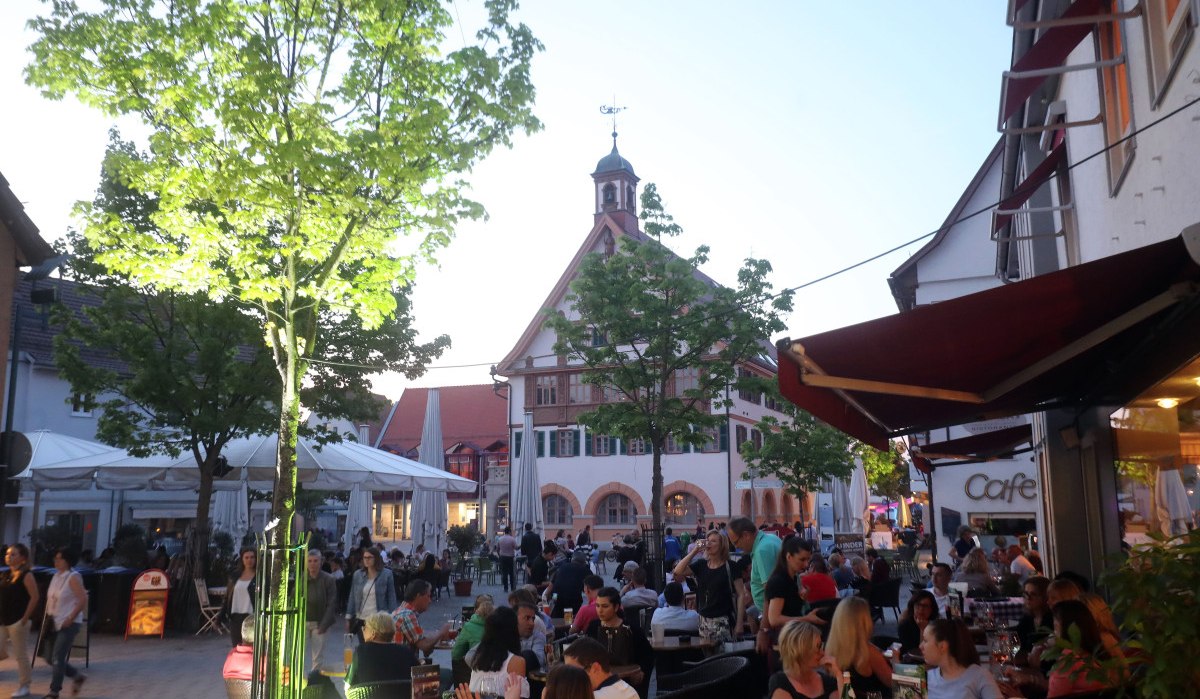 Belebte Café-Szene in der Metzinger Innenstadt mit Blick auf das historische Rathaus im Hintergrund.