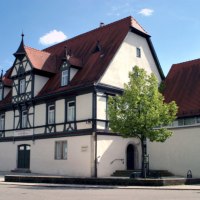 Fachwerkhaus mit rotem Satteldach und dekorativen Giebeln. Ein Baum steht im Vordergrund, der Himmel ist blau mit wenigen Wolken., © Nürtingen - Stuttgart-Marketing GmbH