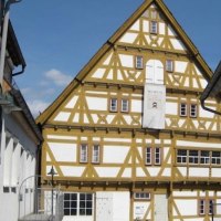 Fachwerkhaus in Waiblingen mit Barockelementen, weiß und gelb gestrichen. Ein Schild weist auf ein Museum hin. Blauer Himmel im Hintergrund., © WTM GmbH Waiblingen