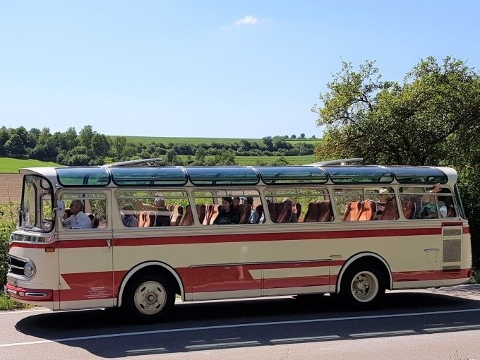 Ein Oldtimerbus mit Glasdach f&auml;hrt durch eine l&auml;ndliche Landschaft der Schw&auml;bischen Alb. Der Himmel ist klar und blau., &copy; SwabianTravel