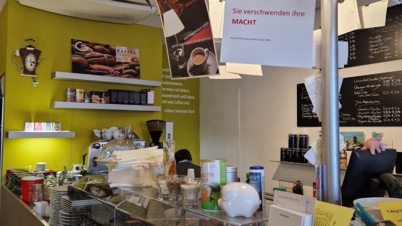 Ein Caf&eacute; mit einer Theke voller Tassen, einer Kaffeemaschine und h&auml;ngenden Schildern. Brosch&uuml;ren und Flyer sind auf der Theke ausgelegt., &copy; StadtNuertingen