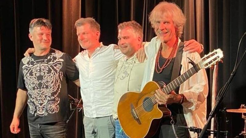 Vier M&auml;nner stehen l&auml;chelnd auf einer B&uuml;hne, einer h&auml;lt eine Gitarre. Sie tragen legere Kleidung und scheinen eine Band zu sein., &copy; Interessengemeinschaft Kultur Sindelfingen / B&ouml;blingen e.V.