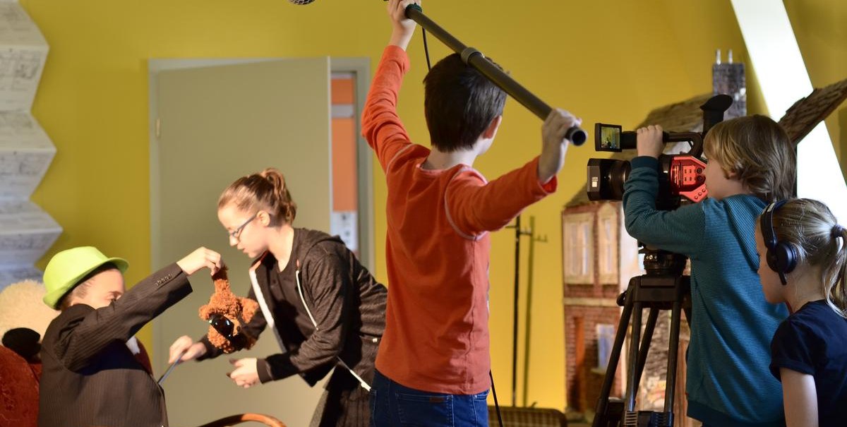Kinder drehen einen Film mit Kamera und Mikrofon in einem Raum. Ein Kind hält ein Plüschtier, während andere filmen und den Ton aufnehmen., © Kinderfilmhaus Ludwigsburg