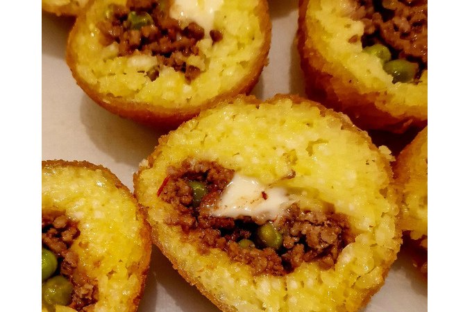 Gefüllte Reisbällchen mit Fleisch und Erbsen, goldbraun frittiert, aufgeschnitten und auf einem Teller angerichtet., © Kultweine-Kochwelten-Kunstücke - Kochschule Sonja Lenz