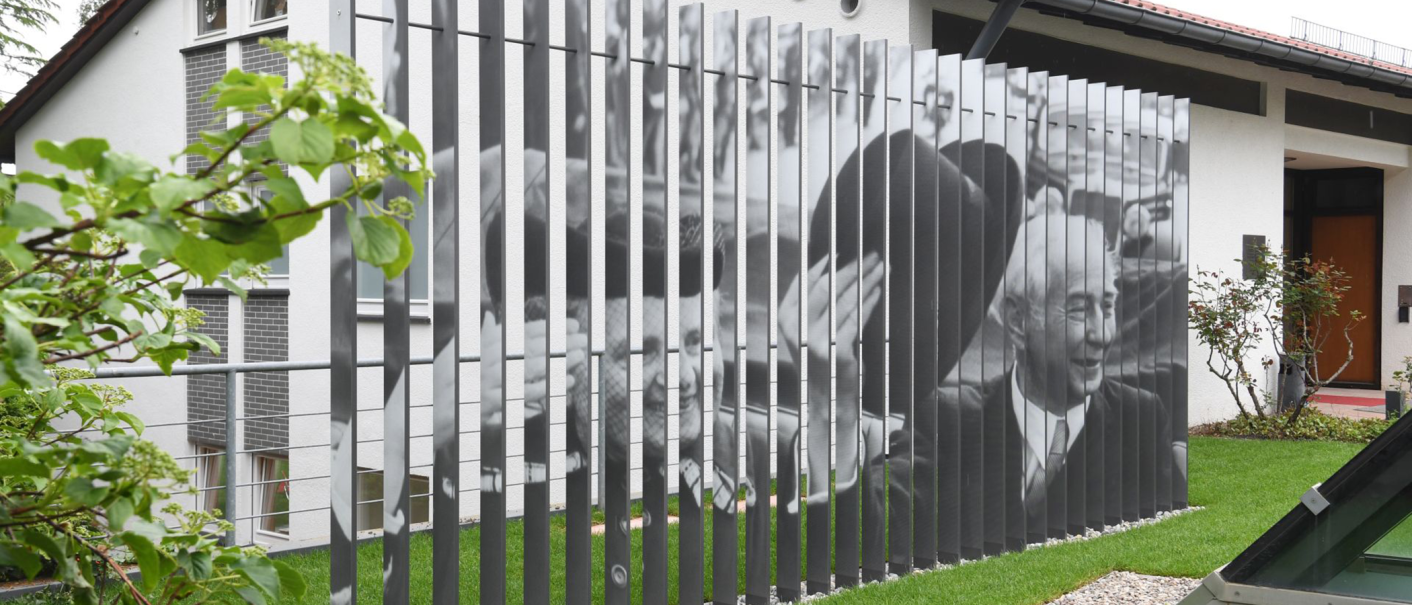 Das Theodor-Heuss-Haus in Stuttgart zeigt eine Fotoinstallation mit schwarz-weißen Bildern auf vertikalen Streben. Im Vordergrund sind Pflanzen zu sehen., © Stiftung Bundespräsident Theodor-Heuss-Haus / Franziska Kraufmann Das Theodor-Heuss-Haus in Stuttgart zeigt eine Fotoinstallation mit schwarz-weißen Bildern auf vertikalen Streben. Im Vordergrund sind Pflanzen zu sehen., © Stiftung Bundespräsident Theodor-Heuss-Haus / Franziska Kraufmann