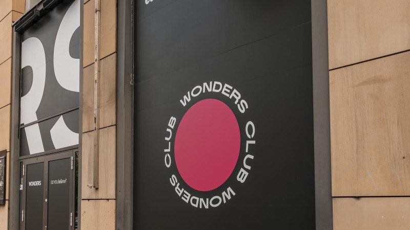 Eingang des Wonders Club mit großem Logo und Schriftzug an der Fassade. Schwarze Türen und ein pinker Kreis mit dem Text 'Wonders Club'., © Stuttgart Marketing GmbH, Sarah Schmid