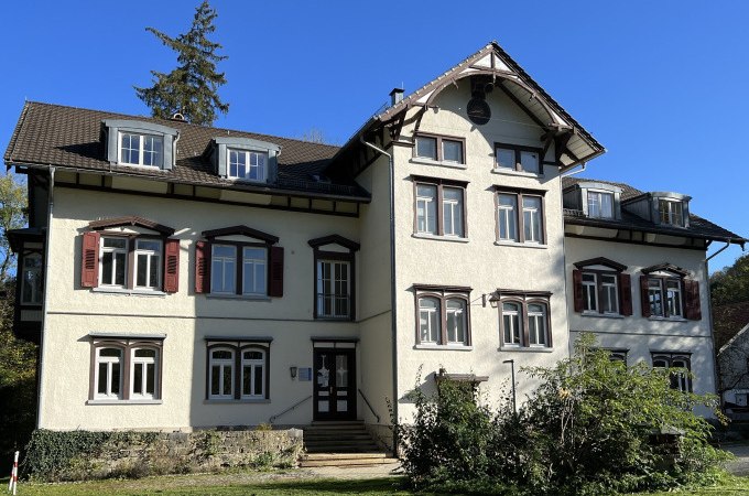 Ein historisches Geb&auml;ude mit wei&szlig;er Fassade und roten Fensterl&auml;den, umgeben von B&auml;umen und Rasen, bei strahlendem Sonnenschein., &copy; Stadt G&ouml;ppingen